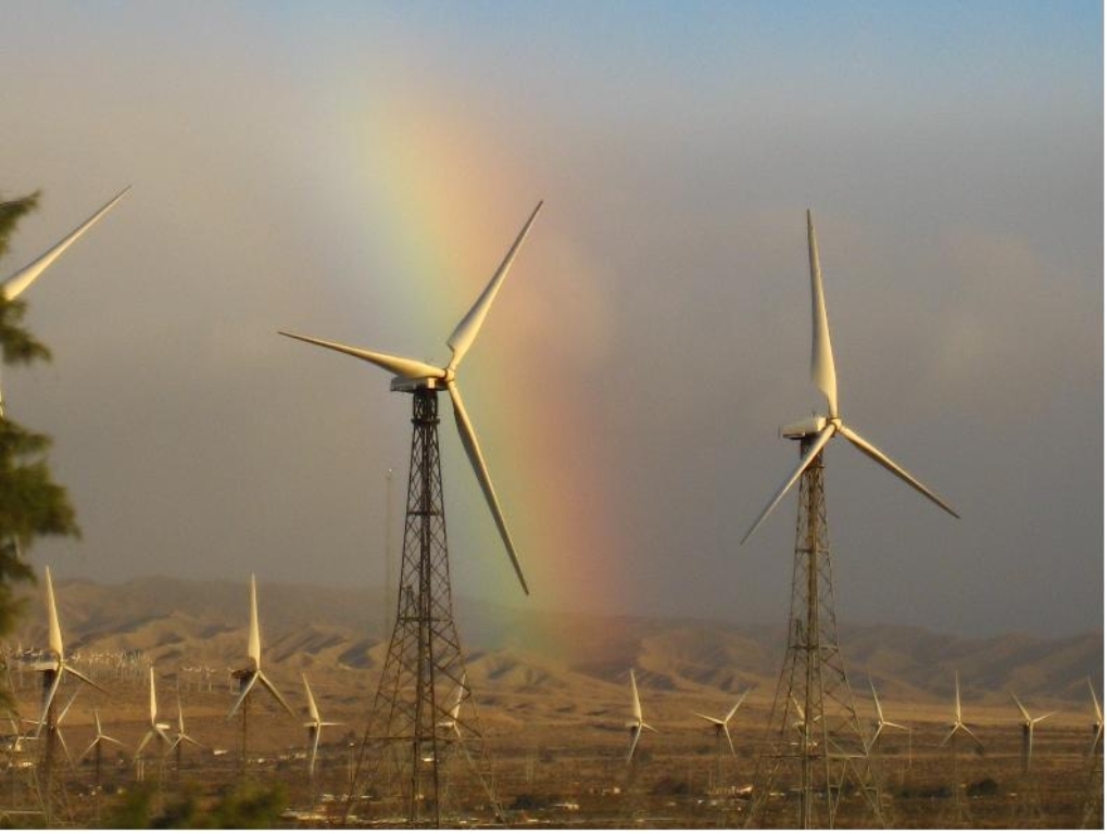 Windmills in the Coachella Valley with a rainbow and desert hills in the distance