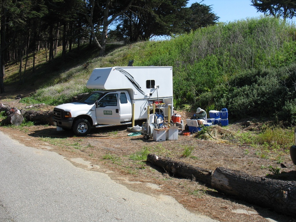 USGS scientist sitting next to USGS lab truck sampling a groundwater well