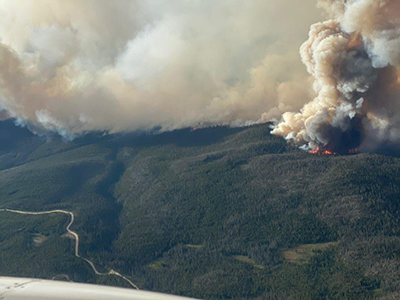 Aerial photo of the Cameron Peak fire on a densely forested ridge showing flames and heavy smoke